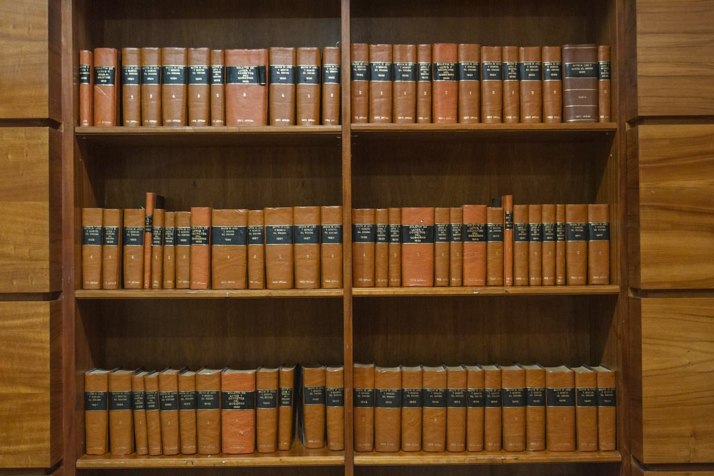 Old law books with cognac covers sit on wooden shelves.